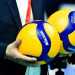 How to Keep Score in Volleyball: A referee holding two Volleyballs in his hand
