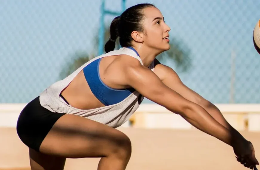 Latest Articles 55 How to Hold Your Hands in Volleyball: Female beach volleyball player in action, focused and performing a dig during a game