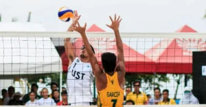 How to Play Beach Volleyball: A male Beachvolleyball Player hitting a ball while another player wants to block