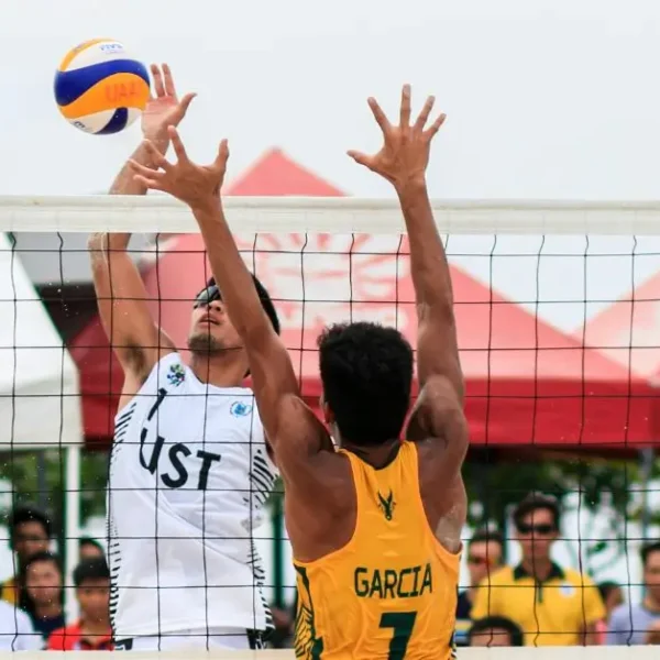 How to Play Beach Volleyball: A male Beachvolleyball Player hitting a ball while another player wants to block