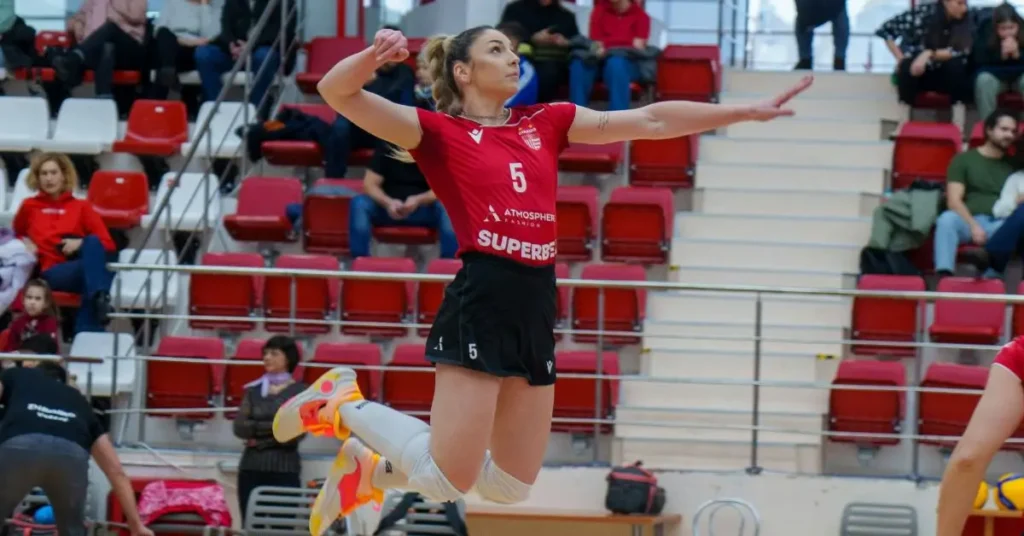 20+ Volleyball Outfits for Women You Want to Wear Every Day! 1 Volleyball Outfits for Women: Women with red jersey, black shorts and white knee pads spiking a volleyball