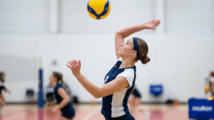 A young female volleyball player with short bob haircut styled into a neat low bun secured with a sports headband on an indoor volleyball court during practice.