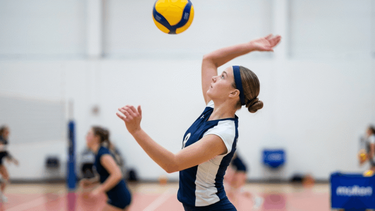 A young female volleyball player with short bob haircut styled into a neat low bun secured with a sports headband on an indoor volleyball court during practice.